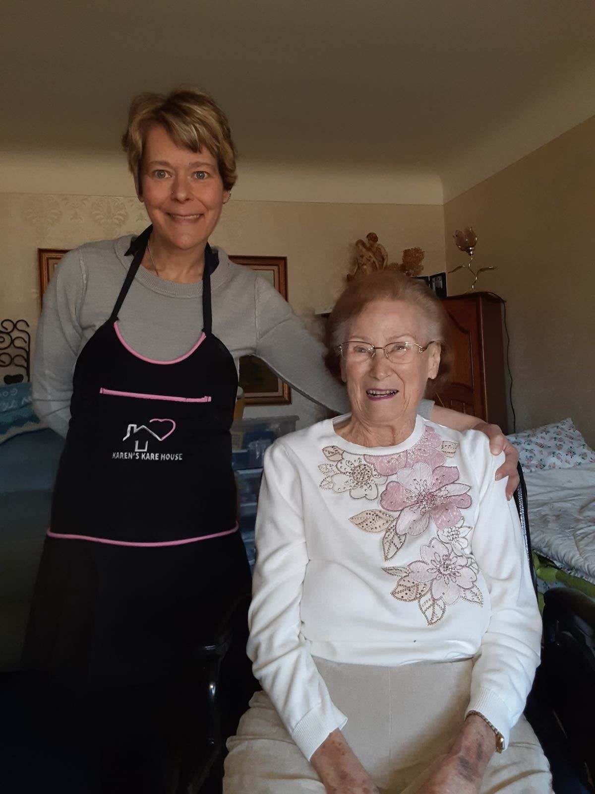 A caregiver and an elderly woman smiling together in a home setting.