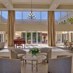A spacious and luxurious living room featuring a high ceiling, large windows, and elegant furnishings.