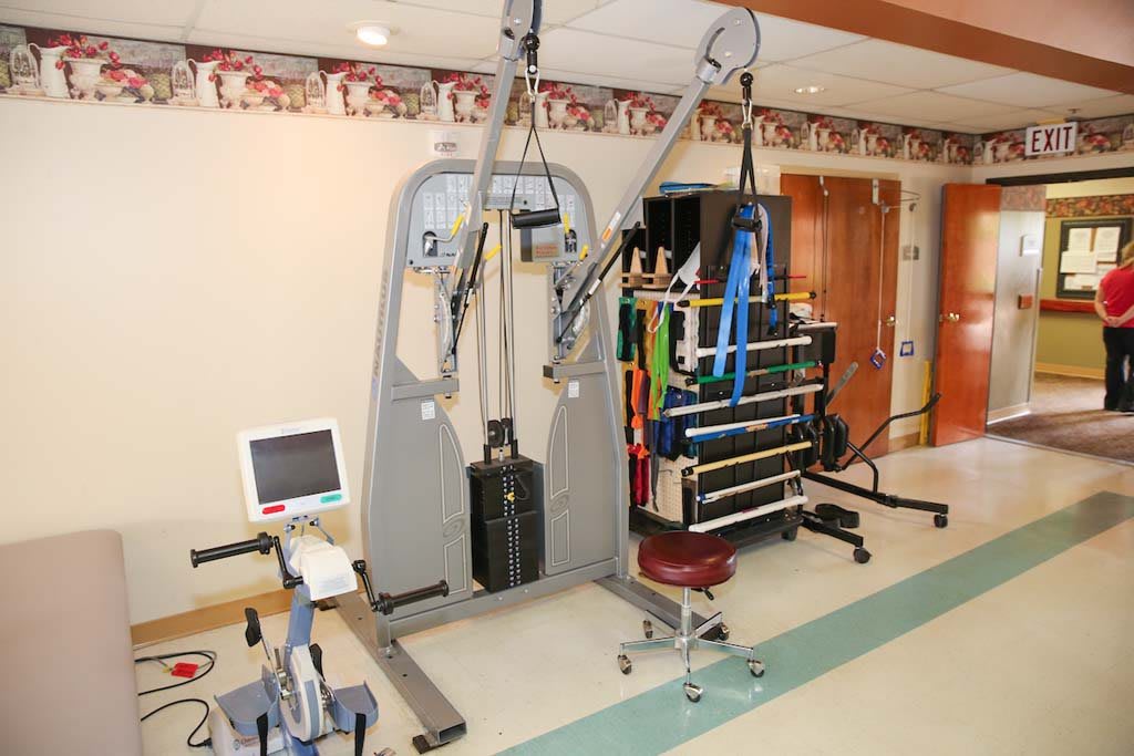 A medical facility room equipped with various rehabilitation and exercise machines for physical therapy.