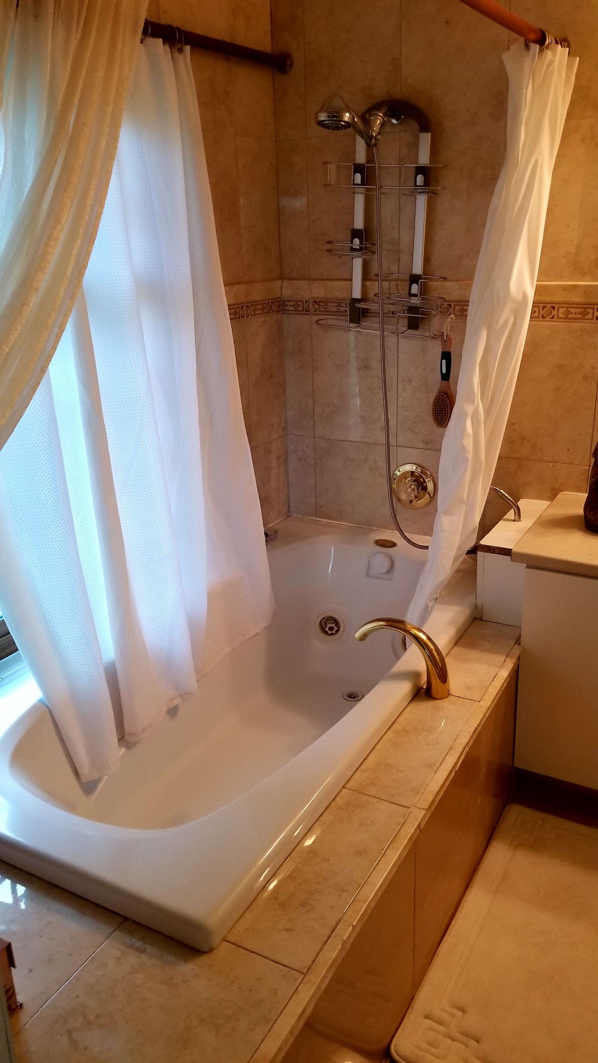 A cozy bathroom with a bathtub and shower setup, featuring a curtain and tiled walls.