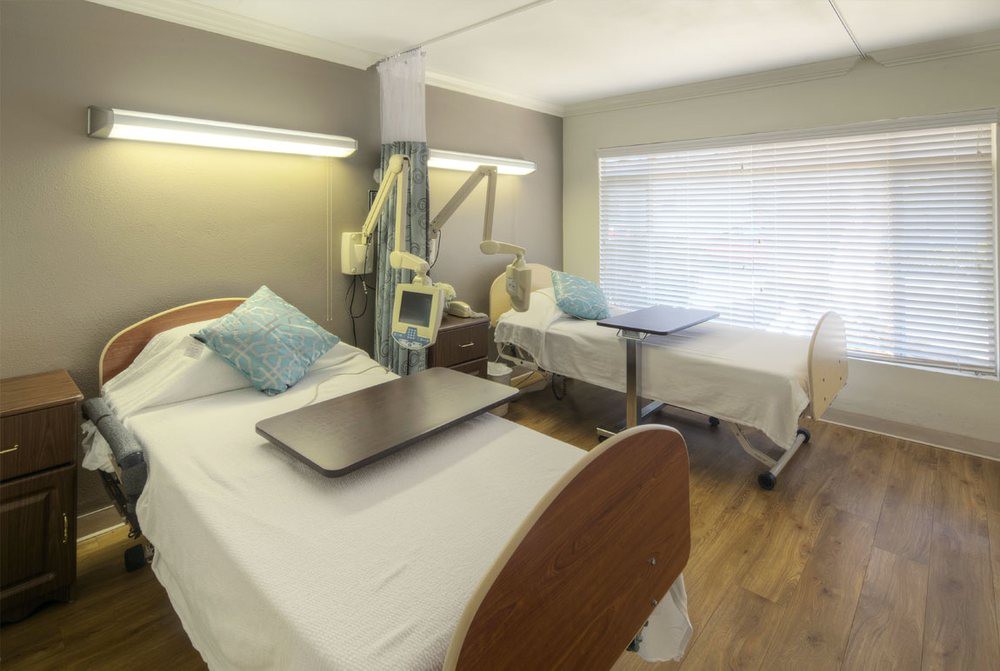 A tidy hospital room with two beds and medical equipment.