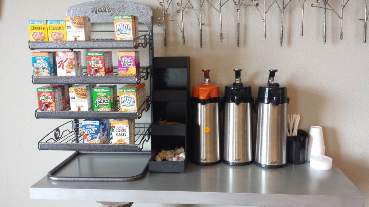 A coffee station featuring beverage dispensers and a display of juice boxes and snacks on the countertop.