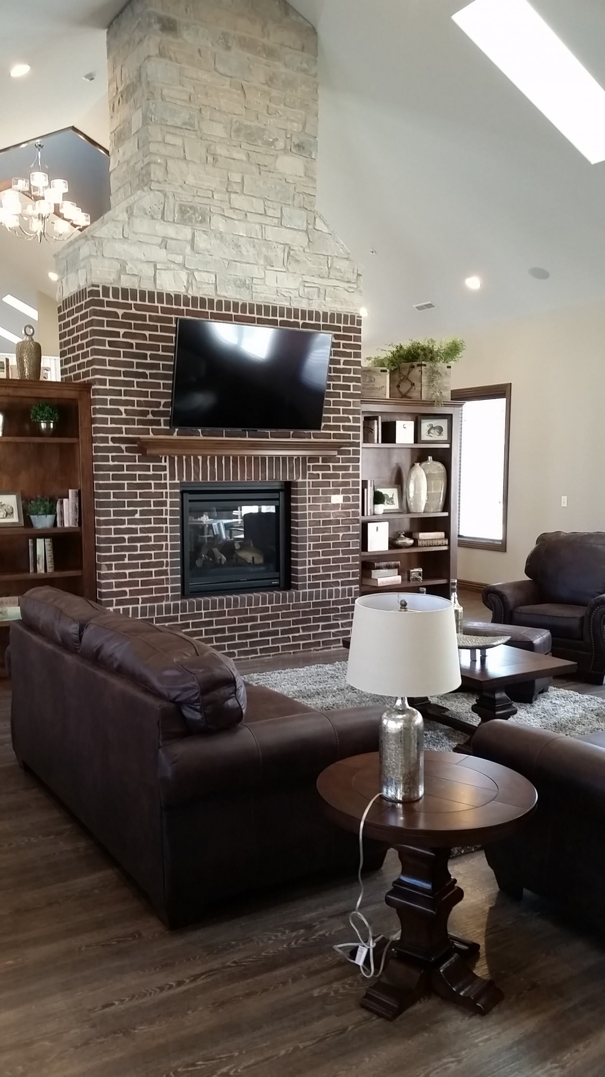 A cozy living room with a brick fireplace, featuring a mounted television and comfortable seating.
