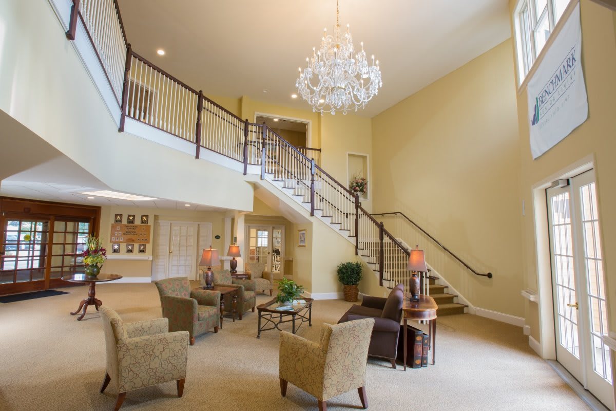 Spacious living area with elegant chandelier and grand staircase.