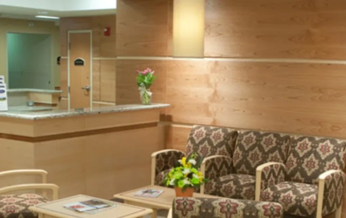 A cozy waiting room with patterned chairs and decorative plants.