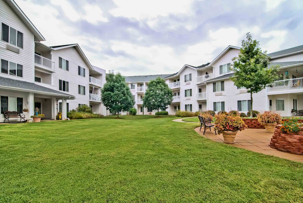 A view of a residential apartment building with a landscaped courtyard and benches.