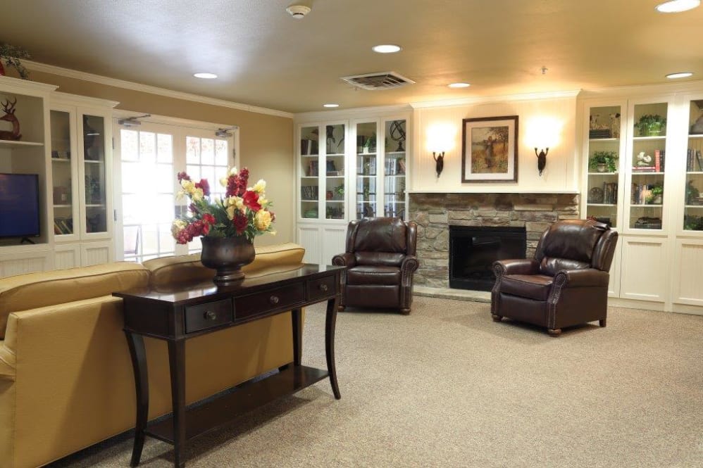 A cozy living room with armchairs, a fireplace, and decorative flowers on a table.