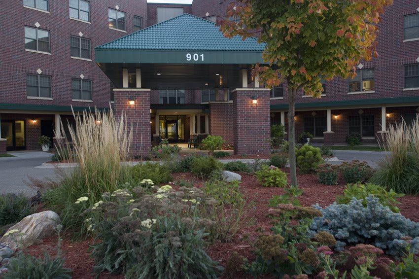 A well-landscaped entrance to a brick building surrounded by greenery.