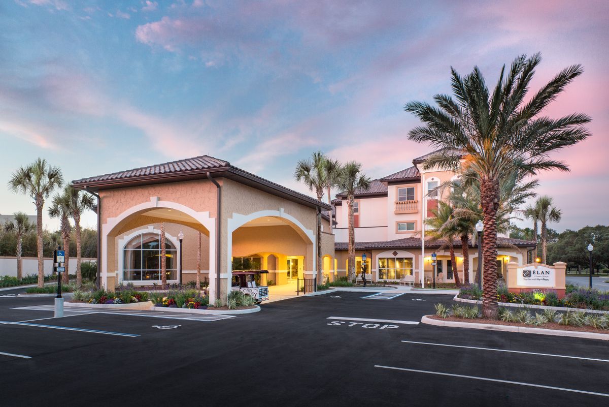 A welcoming hotel entrance at sunset, framed by palm trees.