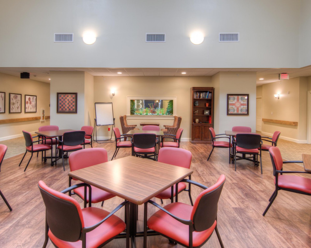 A spacious dining area with multiple tables and chairs, featuring warm lighting and a wood floor.
