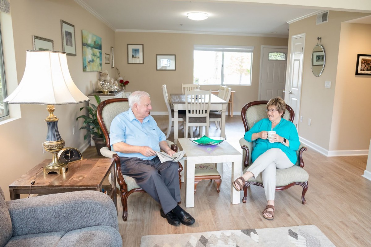 An elderly man and a woman having a conversation in a cozy living room.
