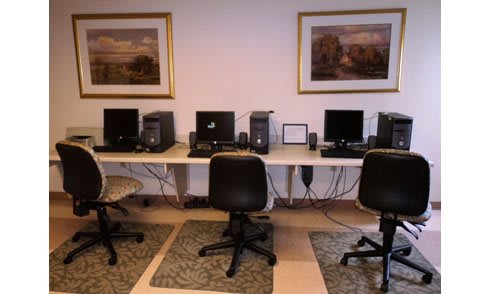 A computer lab with multiple workstations and chairs arranged neatly.