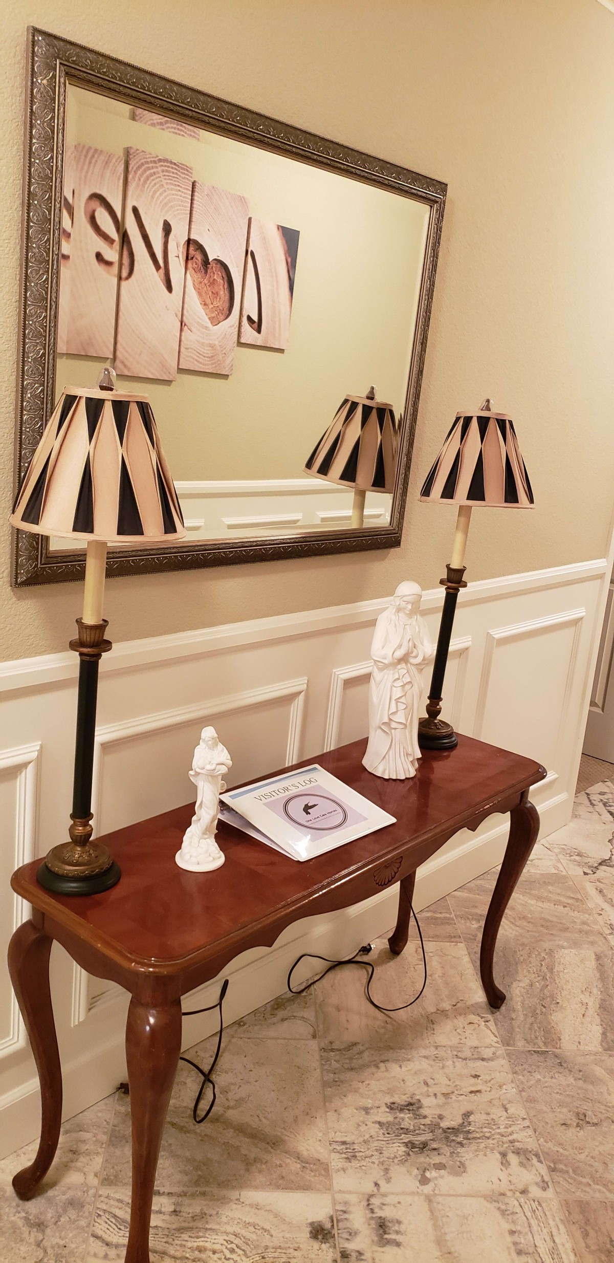 A stylish console table with decorative lamps and statues, placed in front of a mirror.