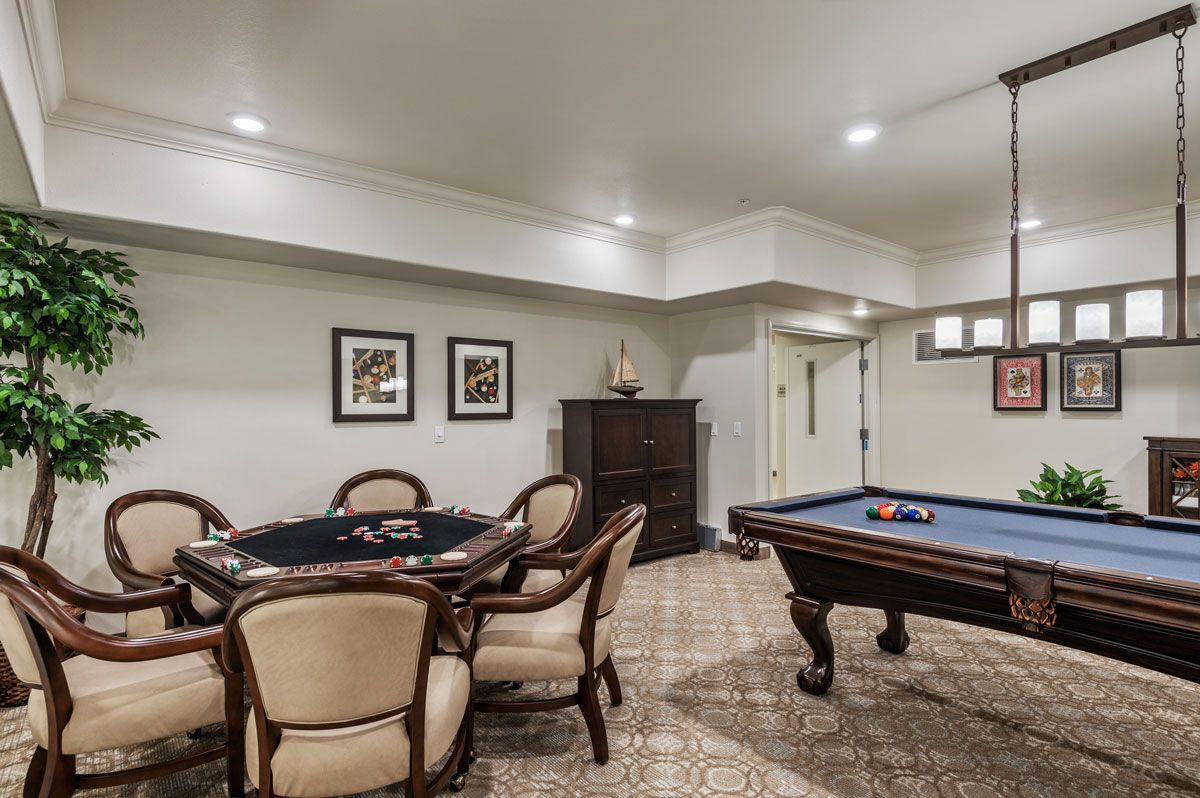 A cozy game room featuring a poker table and a pool table with classic decor.