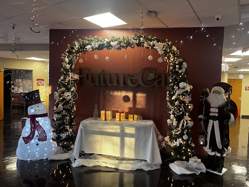 A festive holiday display featuring a floral arch, decorative snowman, and Santa Claus figurine.