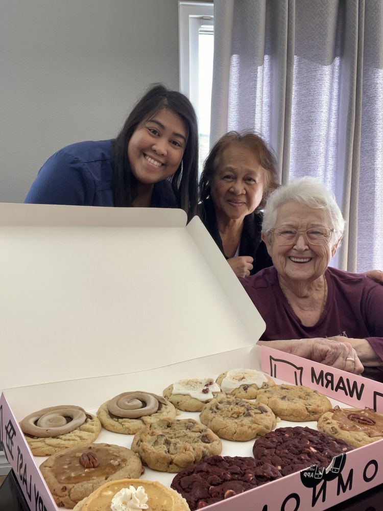 Three people smiling behind a box of cookies.