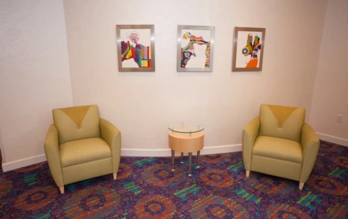 A cozy waiting area with two chairs, a small table, and colorful artwork on the wall.