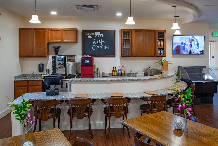 A cozy cafe interior with a wooden counter and seating, featuring coffee machines and a chalkboard menu.