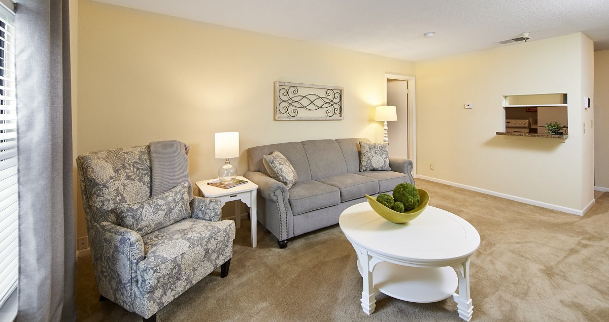 A cozy living room featuring a sofa, armchairs, coffee table, and decorative elements.