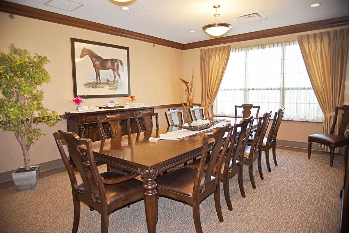 Elegant dining room with a long table, chairs, and horse artwork on the wall.
