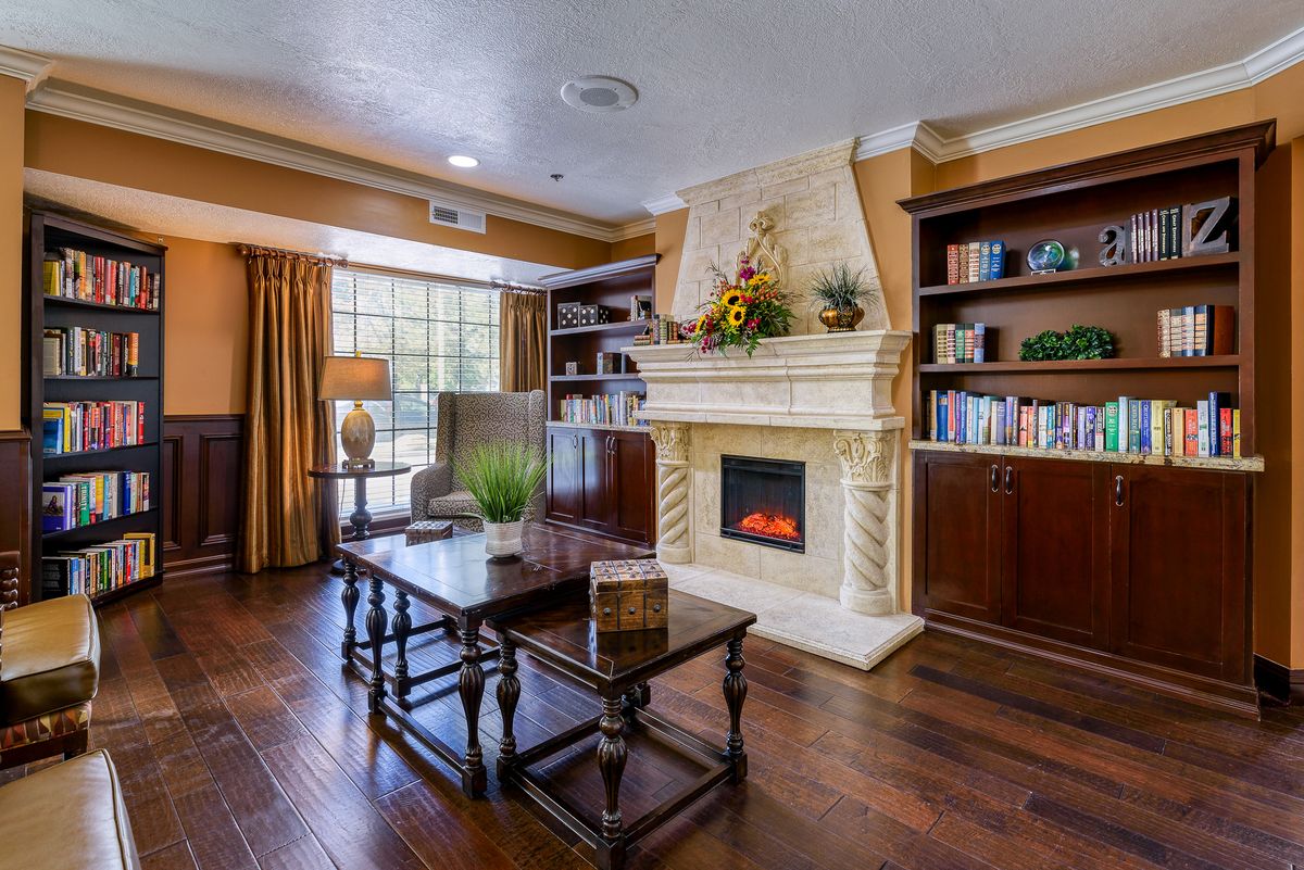 A cozy living room featuring a fireplace, wooden bookshelves, and stylish wooden flooring.