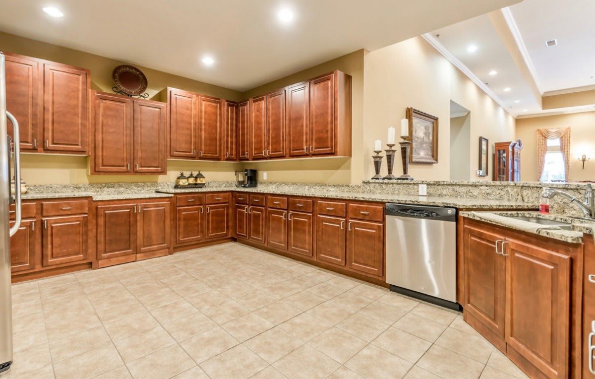 A spacious kitchen with wooden cabinets and granite countertops, featuring modern appliances and recessed lighting.