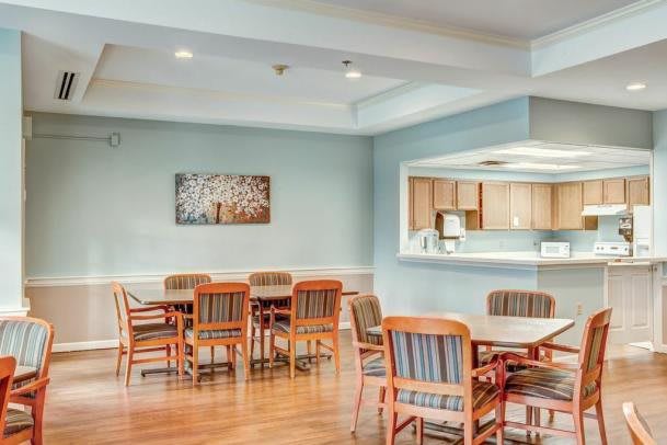A cozy dining area with wooden tables and chairs, adjacent to an open kitchen.