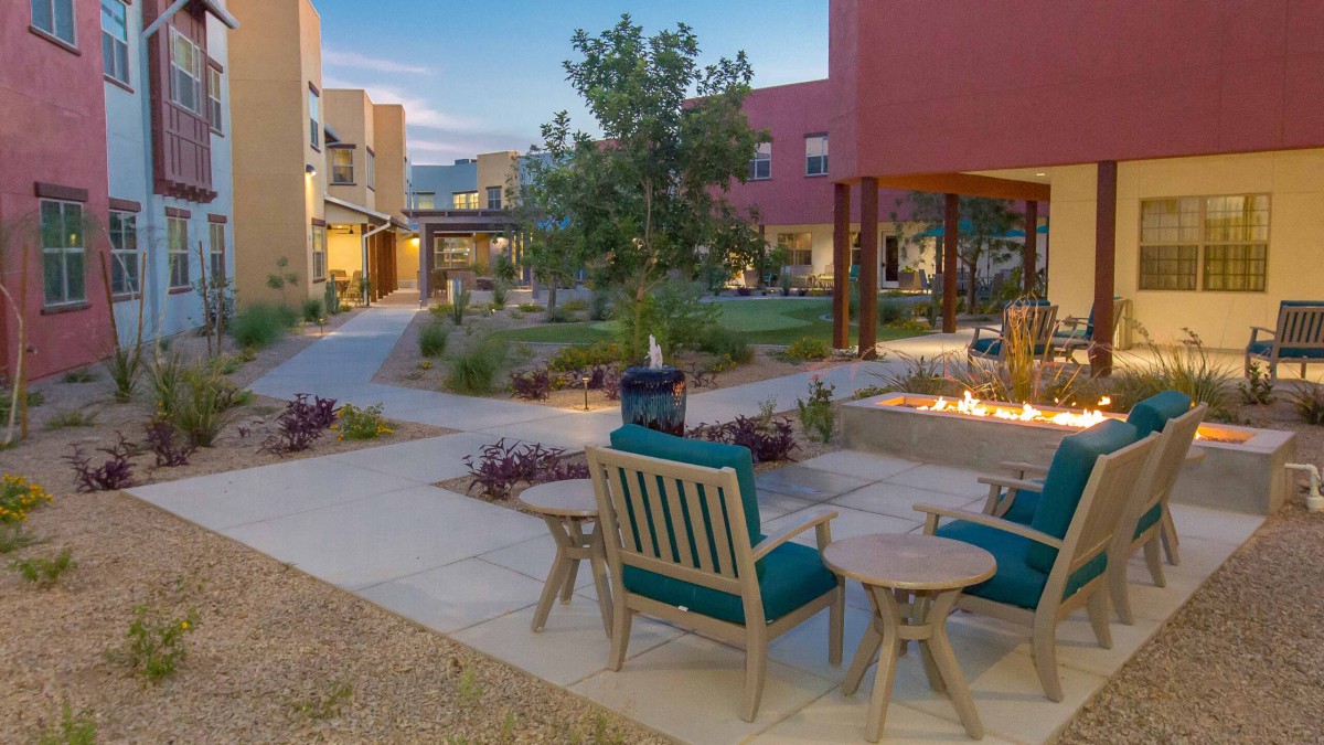 A cozy outdoor patio area with seating and a fire pit surrounded by landscaped gardens.
