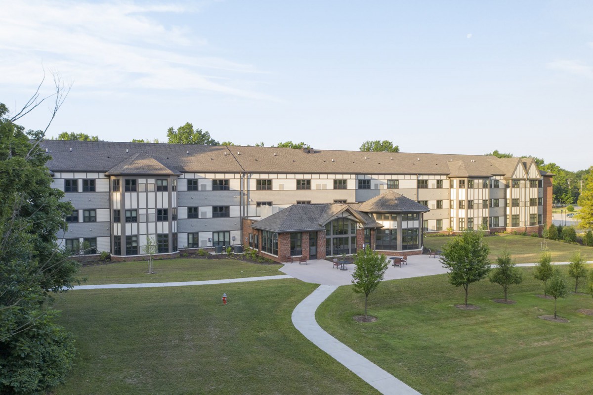A large residential apartment complex with a well-maintained lawn and winding pathway.