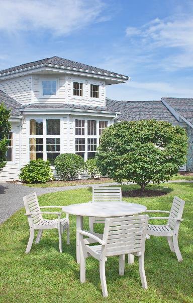 A beautiful suburban house with a well-maintained garden and patio furniture in the yard.