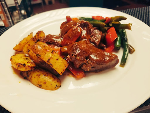 A hearty meal featuring tender meat, seasoned potatoes, and a side of colorful vegetables.