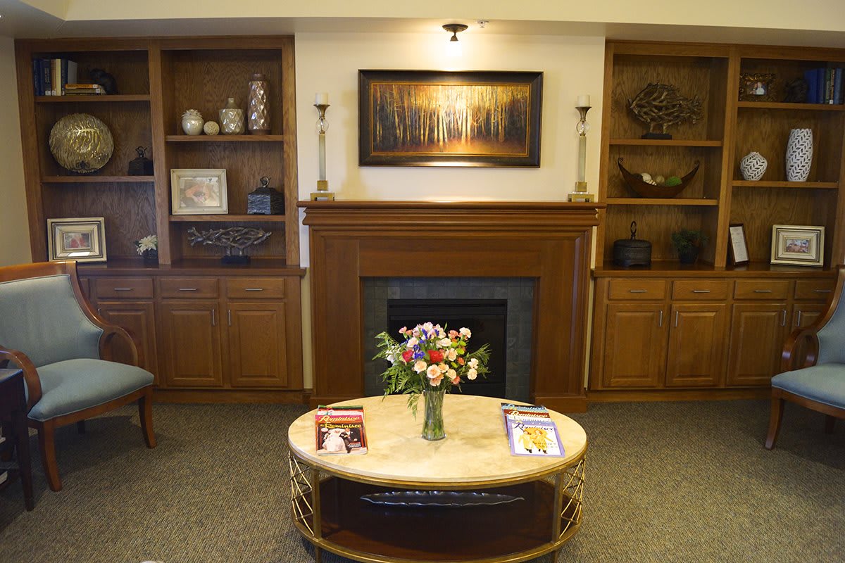 A cozy living room with a central fireplace, bookshelves on either side, and a coffee table adorned with a flower arrangement.