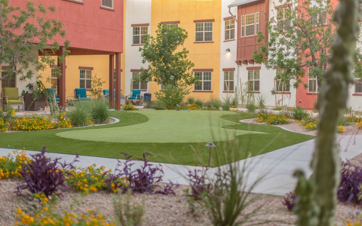 A colorful apartment complex courtyard with landscaped greenery and pathways.