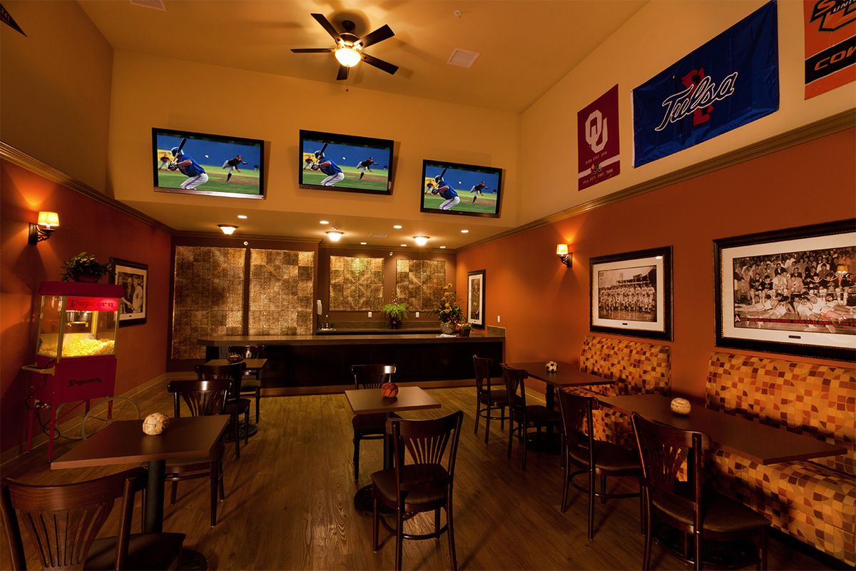 A cozy bar with multiple TV screens showing sports and empty seating areas.