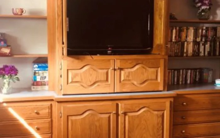 A wooden cabinet with a television and bookshelf.