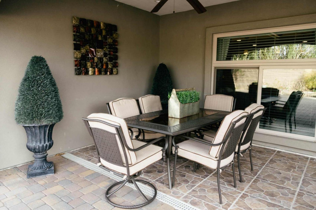 A cozy outdoor patio area with a dining table and six cushioned chairs.