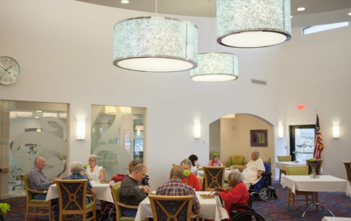A cozy dining room with several people seated at tables under elegant chandeliers.