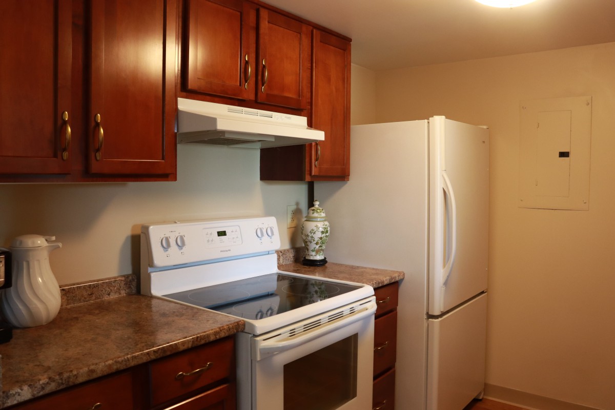 A kitchen with wooden cabinets, a white stove, and a refrigerator.