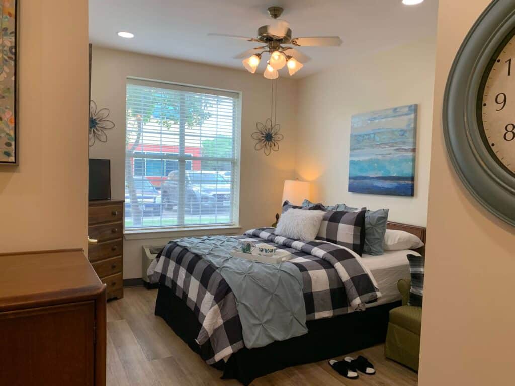A cozy bedroom with a neatly arranged bed, stylish decor, and large window.