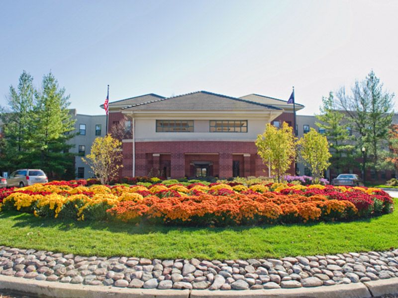 A scenic view of a building surrounded by vibrant gardens and lush trees on a sunny day.