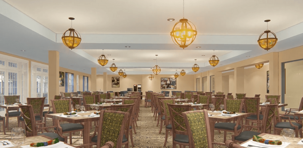 A spacious dining area with multiple tables and chairs, illuminated by elegant chandeliers.