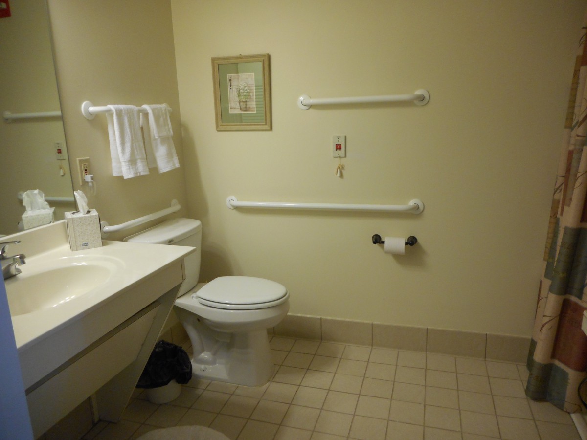 An accessible bathroom with handrails, a toilet, and a sink.