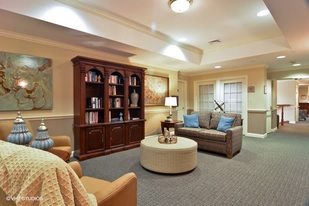 A cozy living room with a bookshelf, sofa, armchair, and coffee table.