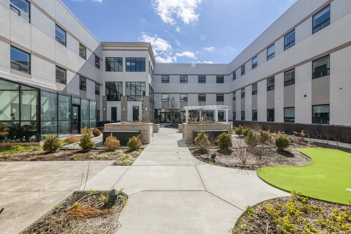 A modern building featuring a landscaped courtyard under a clear sky.