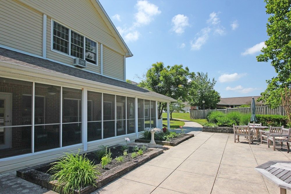 A spacious backyard patio with a screened porch and well-maintained landscaping on a sunny day.