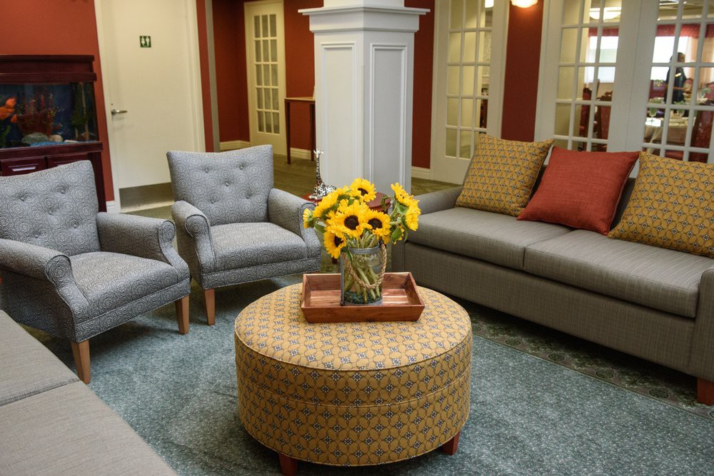 A cozy living room with a sofa, two chairs, and a coffee table adorned with sunflowers.
