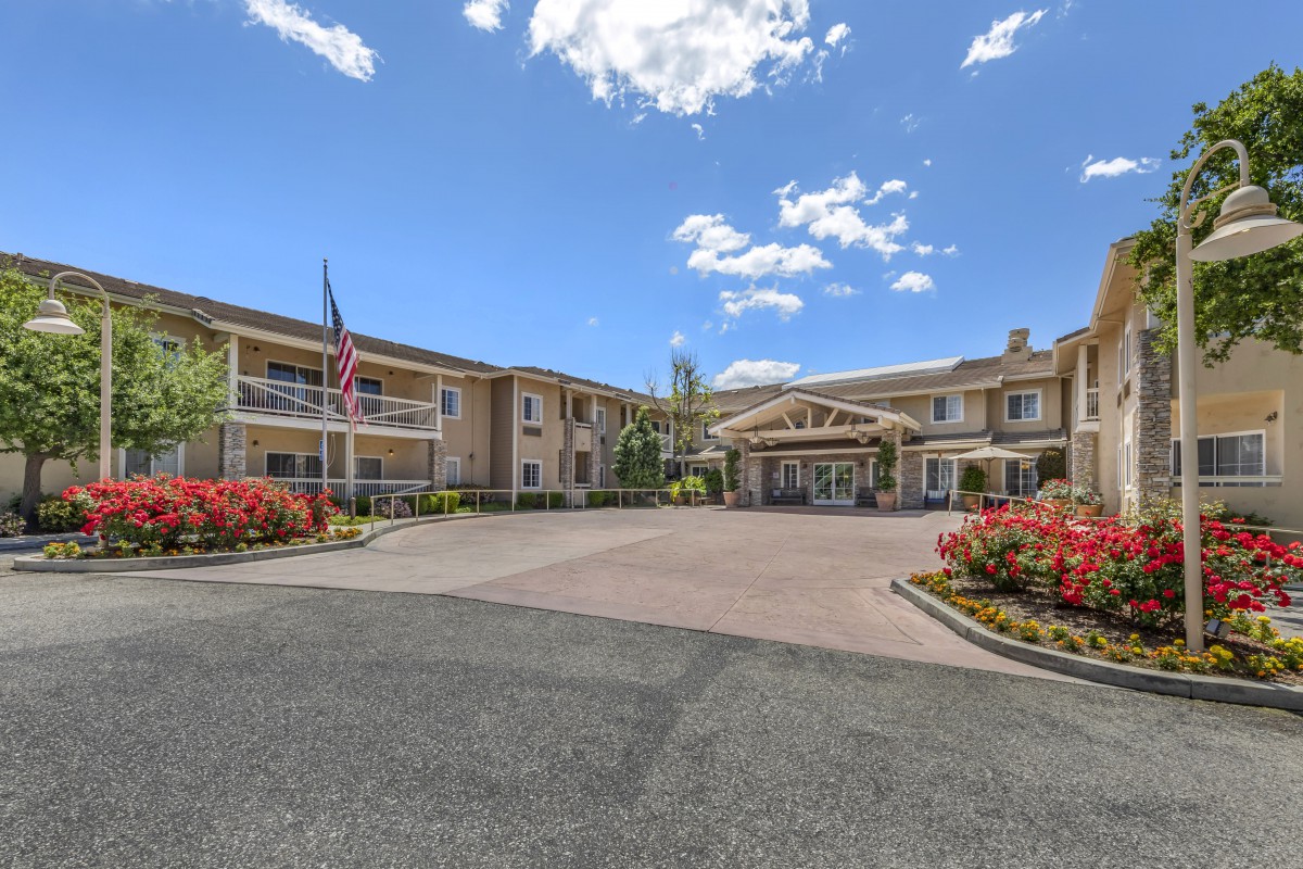 A hotel building with an entrance and well-maintained landscaping under a partly cloudy sky.