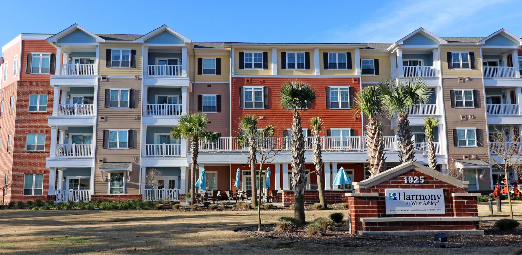 A multi-story apartment building with balconies and palm trees in front.
