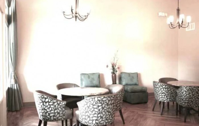 A cozy dining area with patterned chairs and a round table, illuminated by a chandelier.