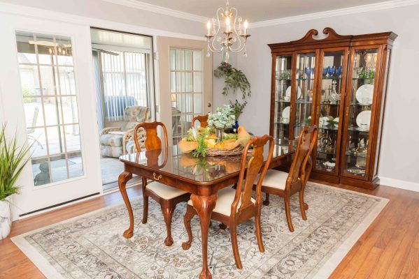A classic dining room featuring a wooden table, chairs, and a china cabinet, illuminated by a chandelier.
